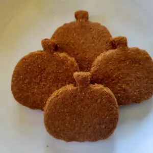 A white plate topped with four cookies covered in cinnamon.